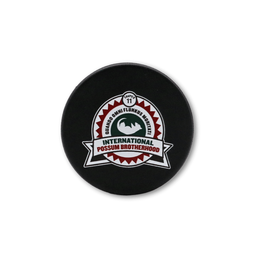 The front of a hockey puck with the Possum Lodge crest